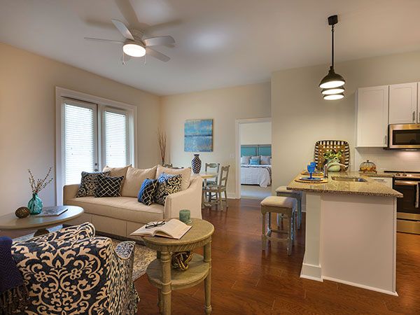 A cozy and modern living space featuring a comfortable sofa, stylish furniture, and an open kitchen with pendant lighting.