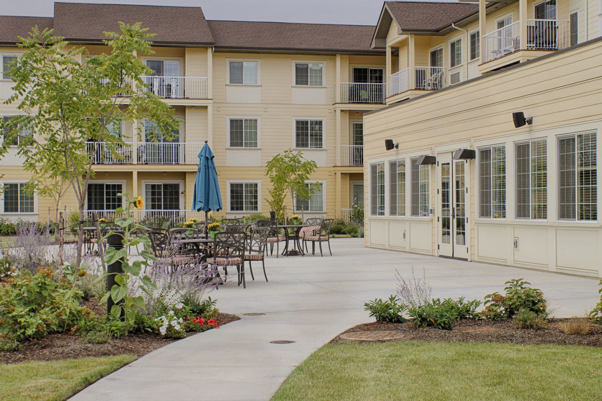 A view of a residential building with a landscaped patio and outdoor seating.