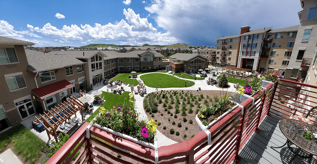 A scenic view of a courtyard surrounded by residential buildings with a landscaped garden in the center under a cloudy sky.