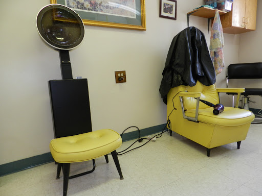 A vintage hair salon setup featuring a yellow chair and a hooded hairdryer.