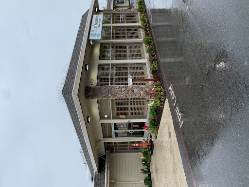 A modern commercial building entrance surrounded by greenery on a rainy day.
