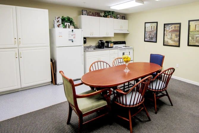 A cozy and functional kitchen and dining area with a wooden table, chairs, white refrigerator, and cabinets.