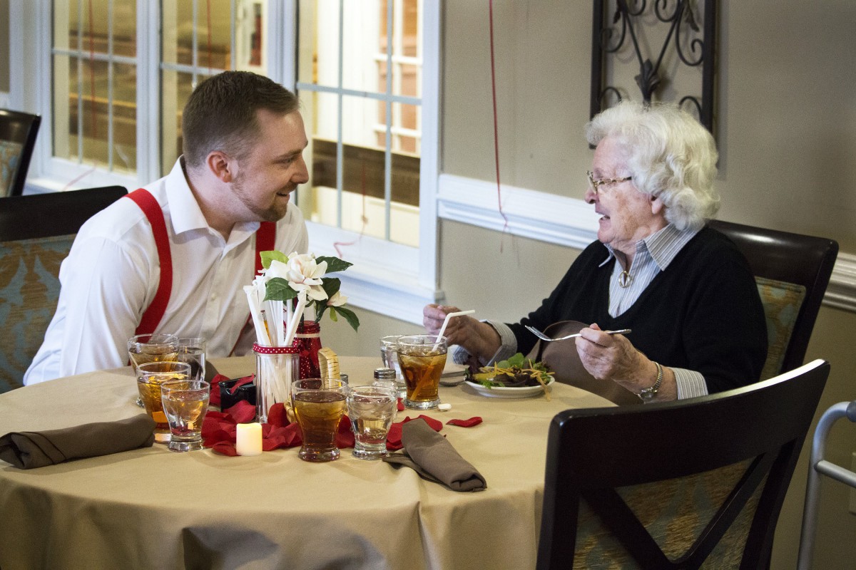 A man and an elderly woman enjoying a conversation over a meal at a restaurant.