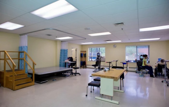 A spacious rehabilitation room equipped with therapy tables and exercise equipment.