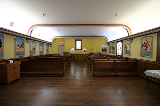 A serene interior view of a church, featuring wooden pews and vibrant yellow walls.
