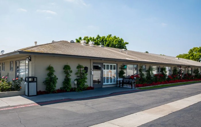 A single-story building with a landscaped entrance under a clear sky.