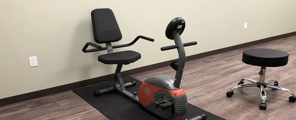 A recumbent exercise bike positioned on a mat in a gym setting.