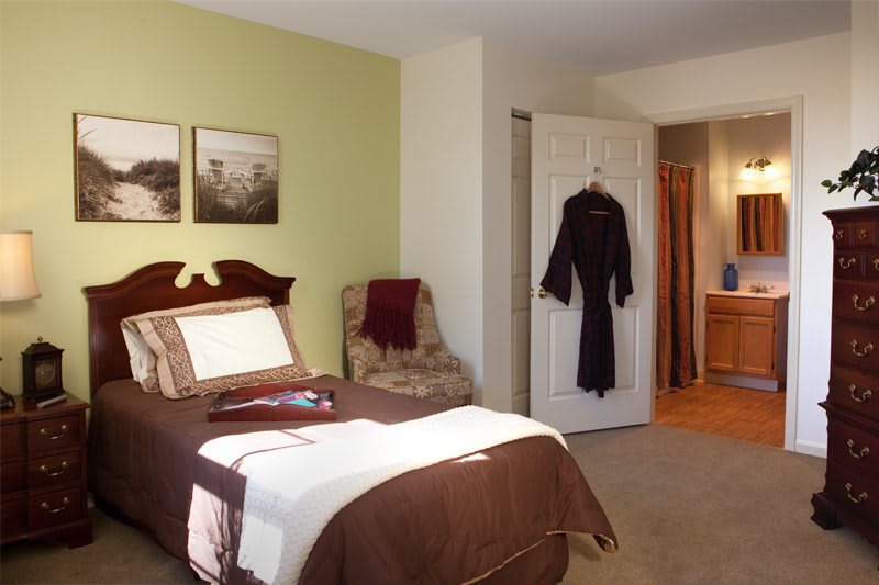 A cozy bedroom with a neatly made bed, an armchair, and soft lighting.
