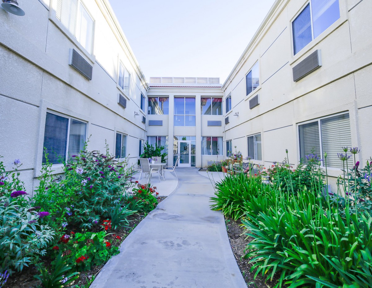 A view of an apartment complex with a garden pathway leading to the entrance.