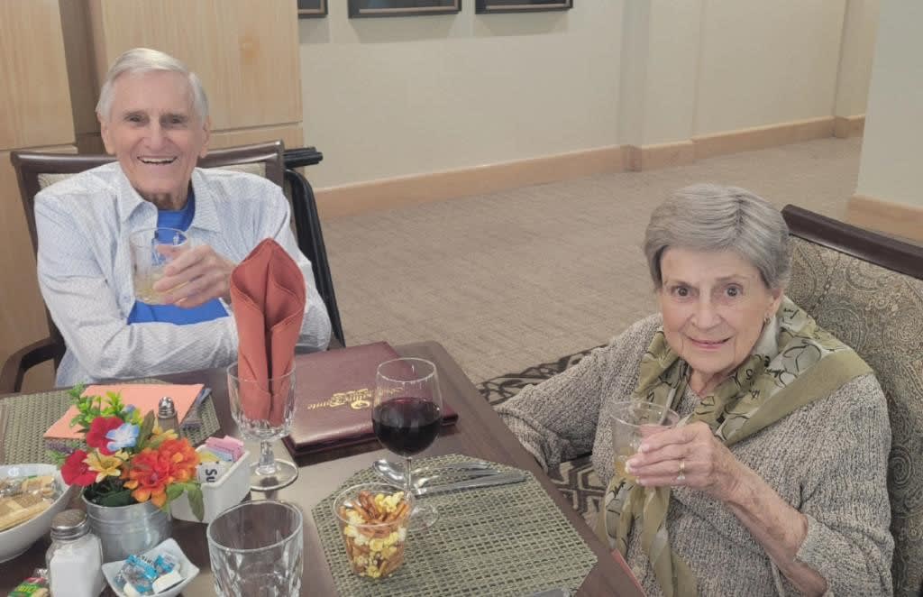 An elderly couple enjoying a meal together at a dining table.