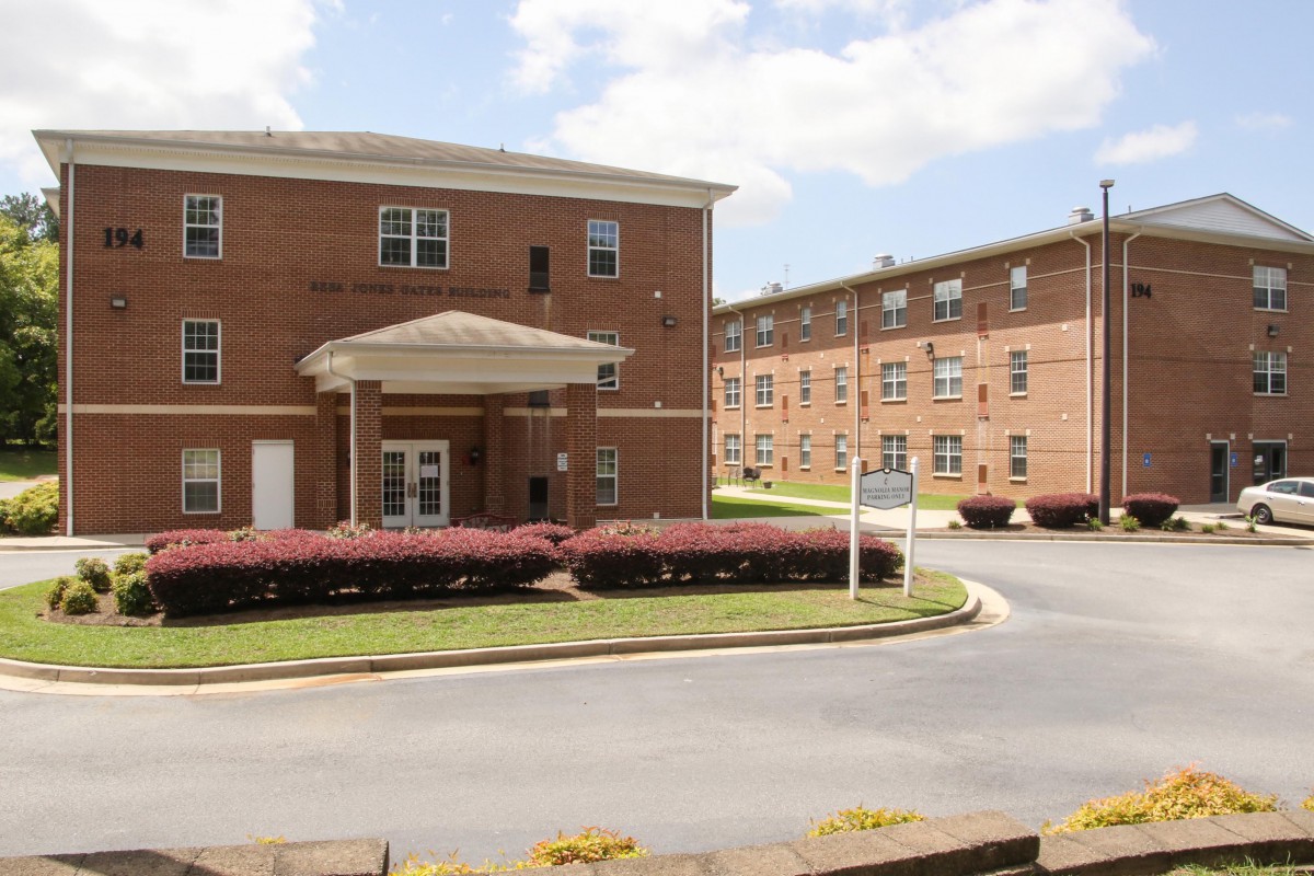 A brick residential building with a landscaped entrance and drive.