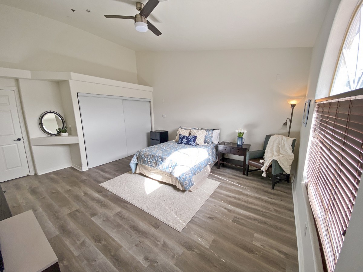A modern and minimalist bedroom with wooden flooring and ample natural light.