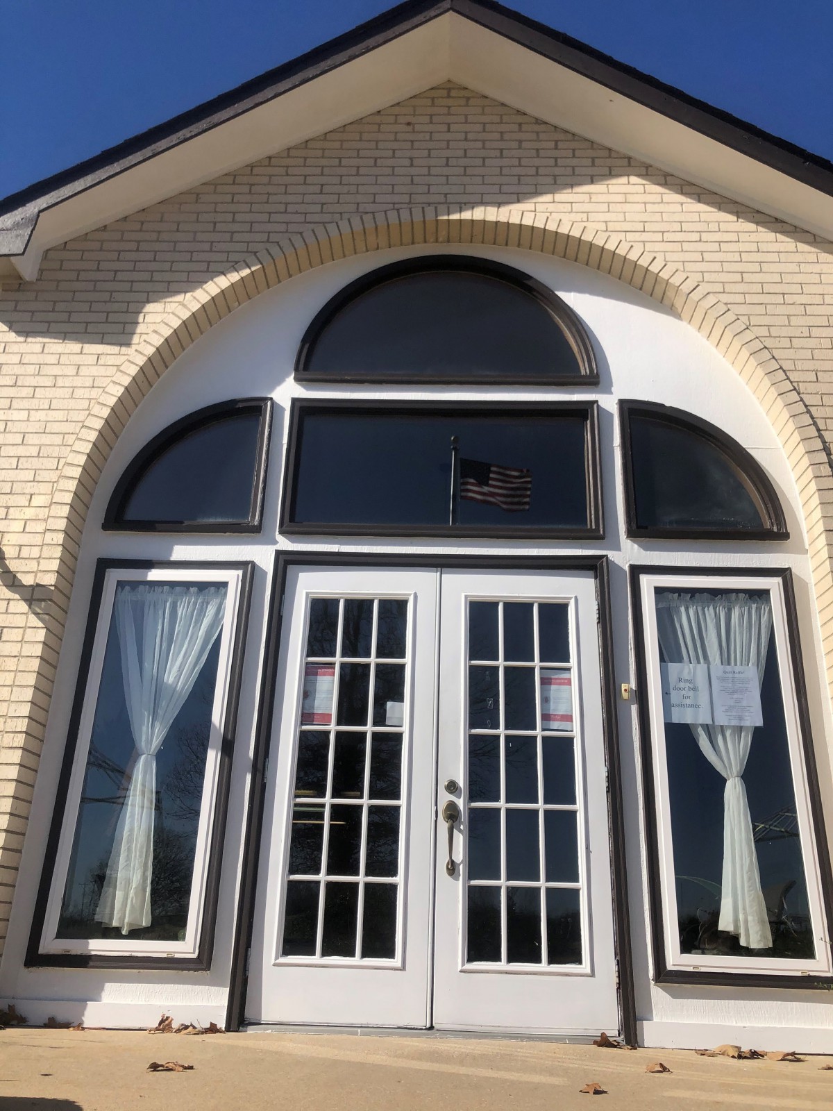 A front entryway with large glass doors and an arched window above, framed by a brick exterior.