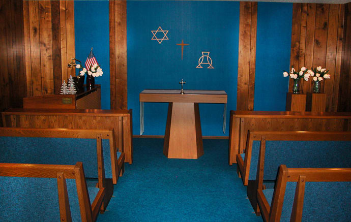 An interfaith chapel featuring an altar and symbols of Christianity and Judaism, with seating for visitors.