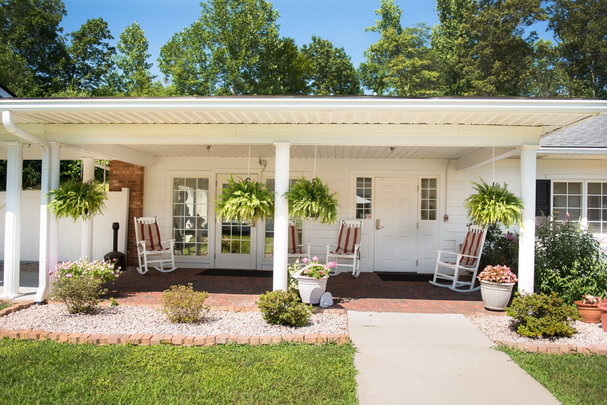 A cozy porch with rocking chairs and lush greenery creates a welcoming outdoor space.