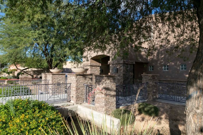 A stone-built structure surrounded by trees and a garden.