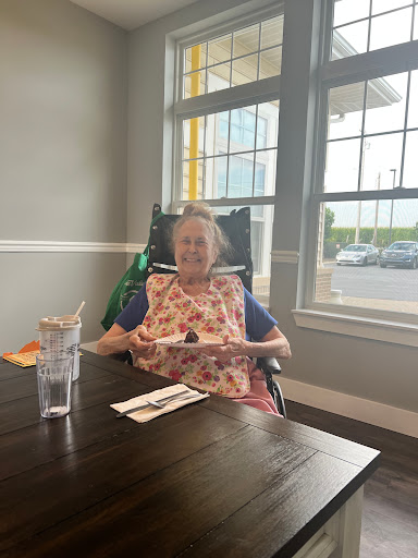 An elderly woman enjoying a meal in a cozy restaurant setting.