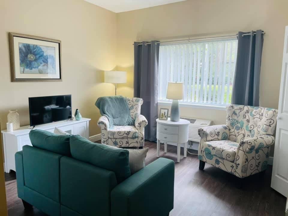 A cozy living room with a sofa, armchairs, and a large window.