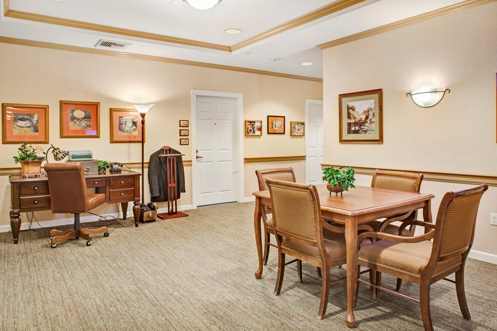 A well-furnished office meeting room with a wooden table, chairs, and decorative artwork on the walls.