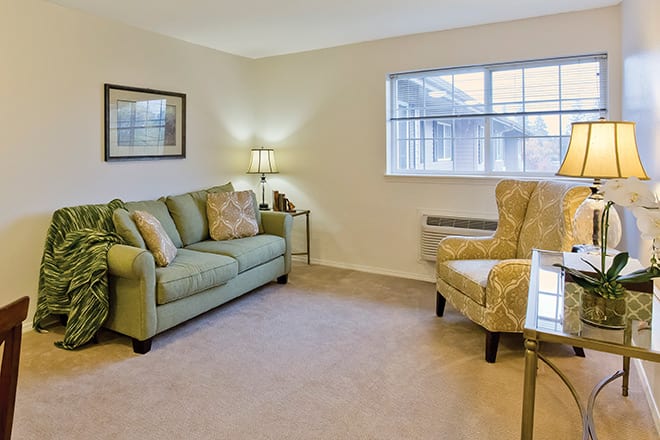 A cozy living room with a sofa, armchair, and soft lighting.