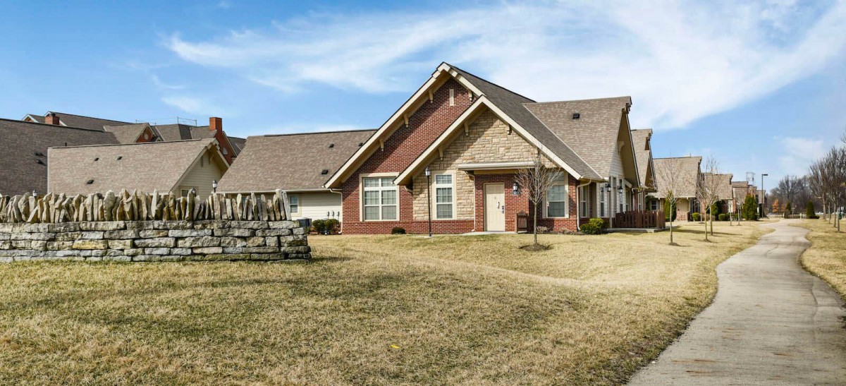 A suburban brick house with a well-maintained lawn under a blue sky.