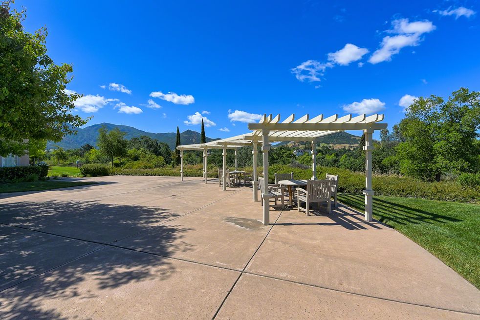 A scenic outdoor patio area with pergolas overlooking a mountainous landscape under a clear blue sky.