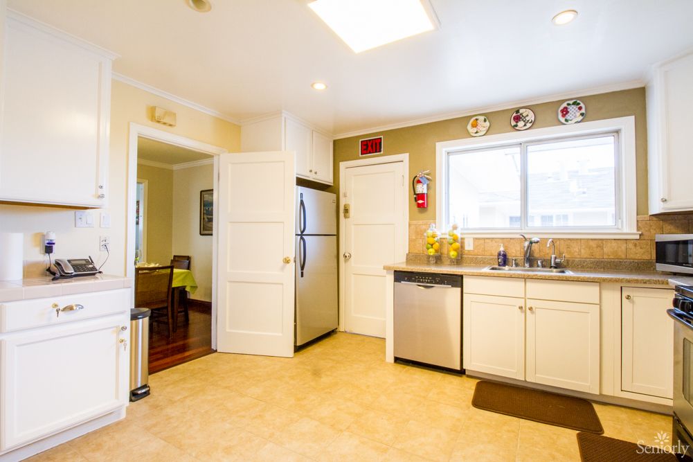 A modern kitchen featuring a refrigerator, dishwasher, and ample cabinet space with natural lighting.