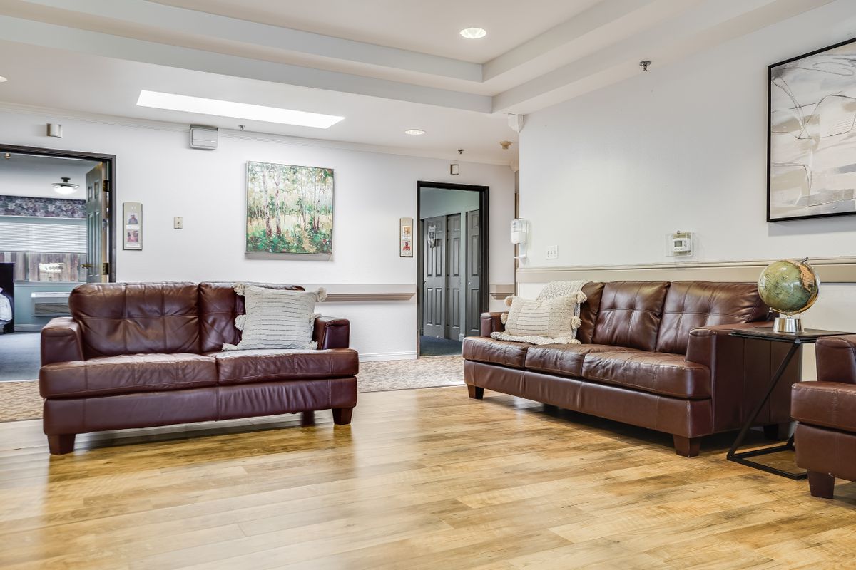 A modern living room with leather sofas and hardwood flooring.