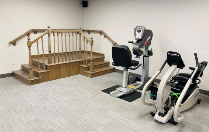 A physical therapy room with exercise equipment and a wooden staircase for rehabilitation exercises.