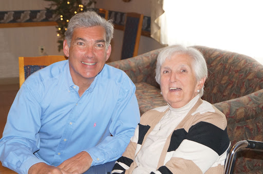 A joyful moment shared between a smiling man and an elderly woman, captured indoors.
