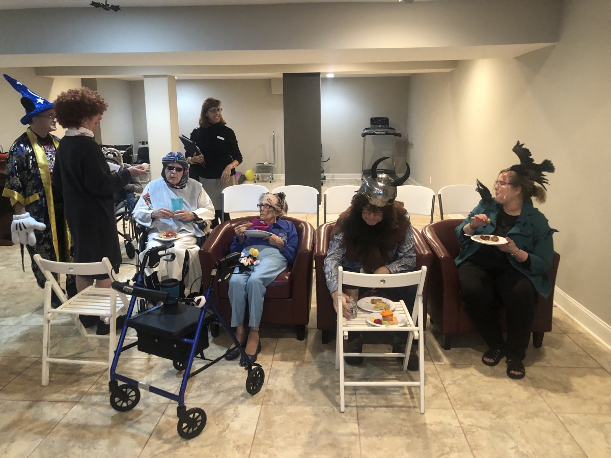 A group of people, some in costumes, sitting indoors at a casual gathering.