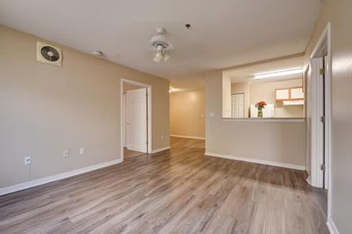 Spacious apartment living area with hardwood floors and a view into the kitchen.