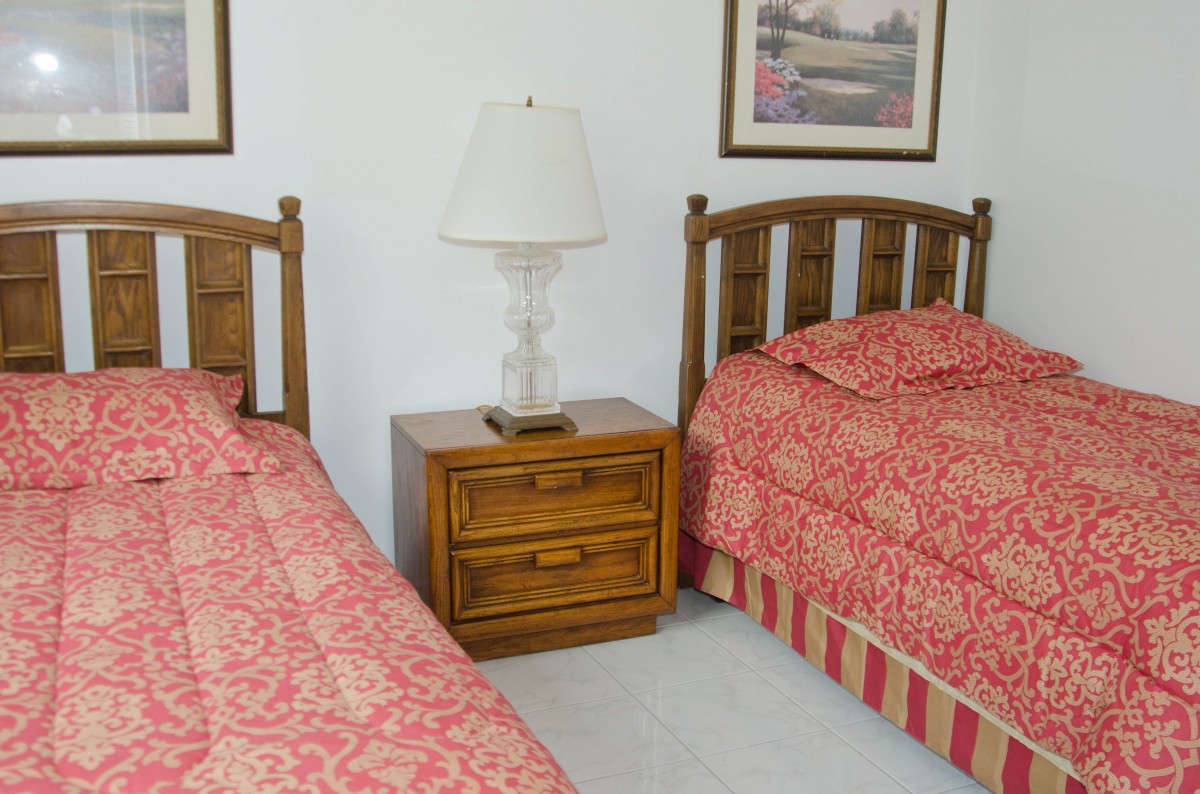 A cozy bedroom with two twin beds, a nightstand, and a decorative lamp.
