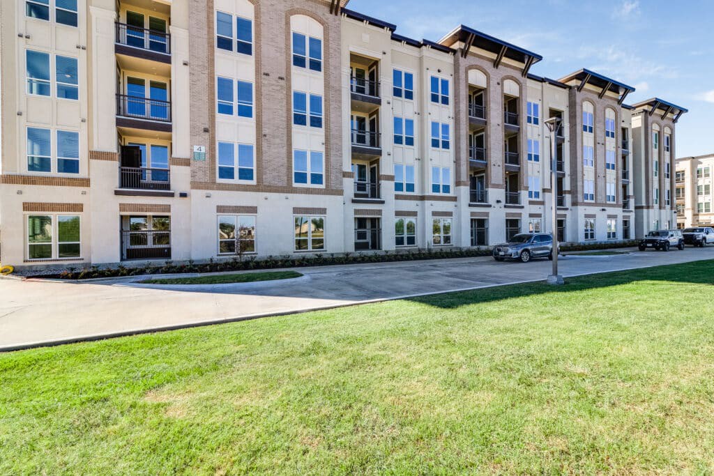 A modern residential apartment complex with a well-maintained lawn.