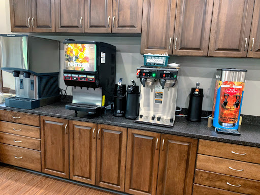 A beverage station featuring a soda machine and coffee dispensers in a kitchen setting.