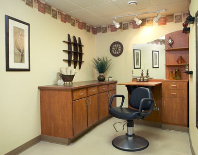 A cozy salon setup featuring a styling chair, mirror, and wooden cabinetry.