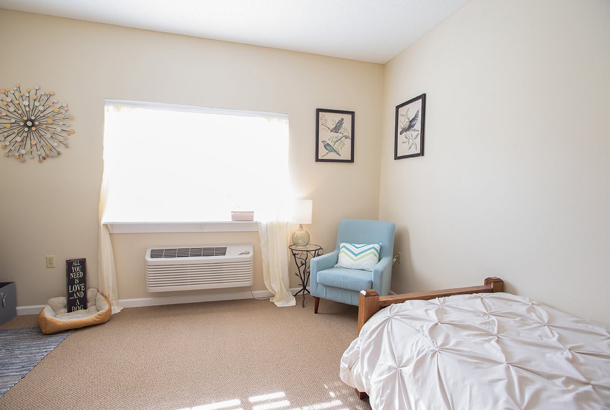 A minimalist bedroom with a comfortable armchair and natural light.