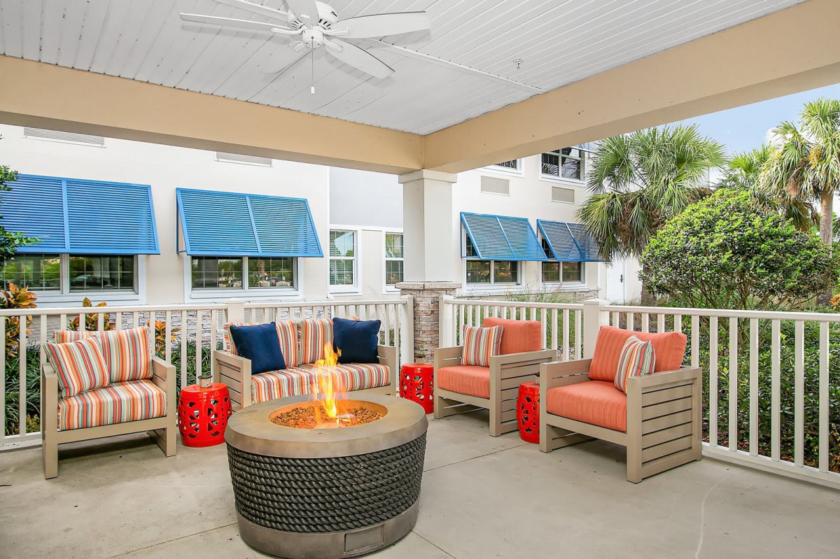 A cozy outdoor patio with comfortable seating and a fire pit under a covered area.