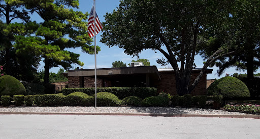 A view of a building with an American flag and well-maintained landscaping.