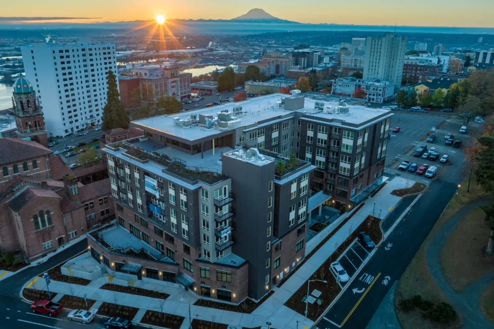 A beautiful sunrise over a cityscape featuring an urban building with a distant mountain view.