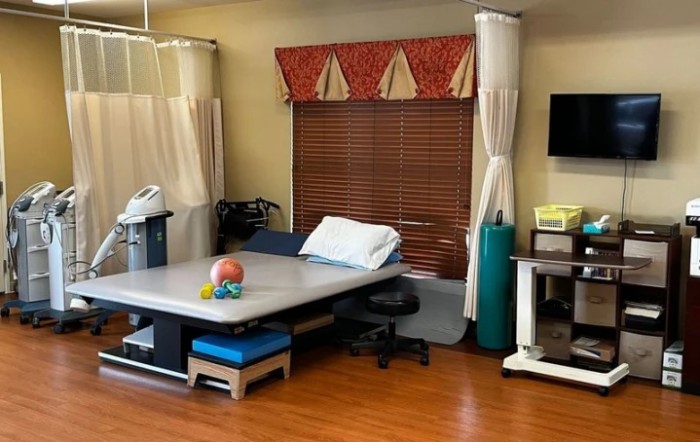 A physical therapy room equipped with a treatment bed and exercise equipment.