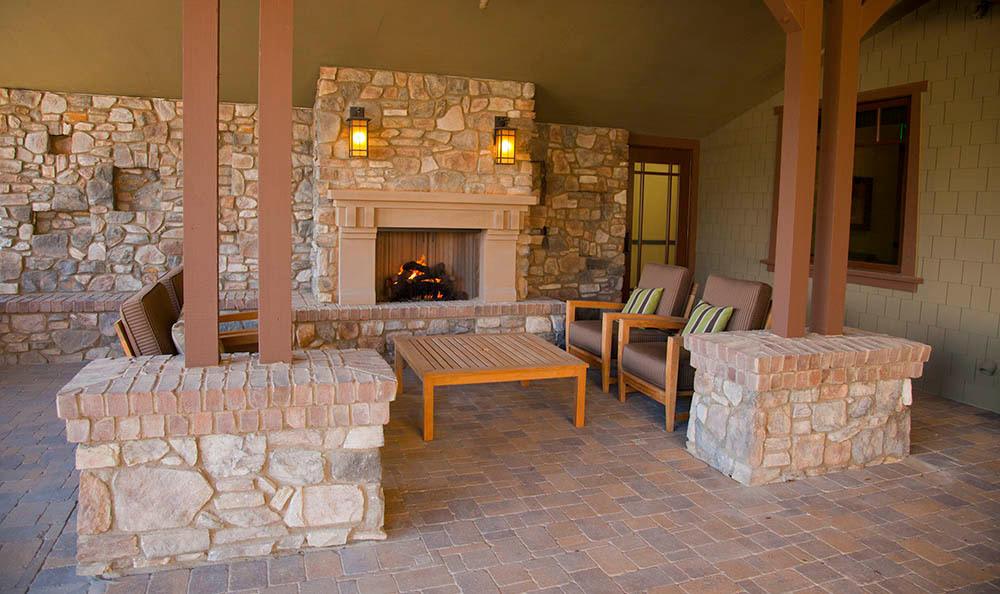A cozy outdoor patio featuring a stone fireplace and comfortable seating.