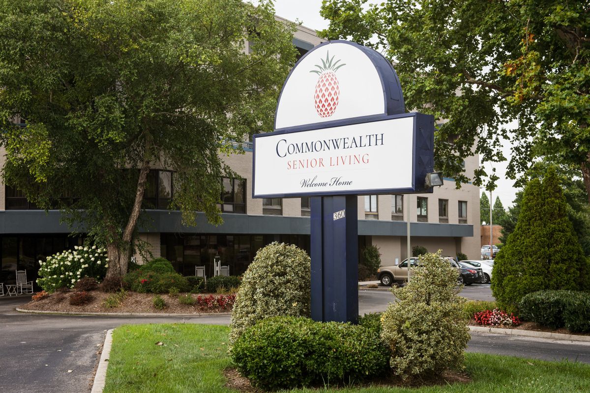A sign for Commonwealth Senior Living stands amidst landscaped greenery in front of a multi-story building.