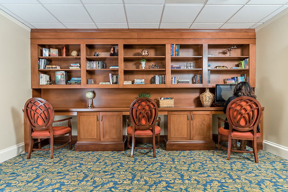 A cozy library space with wooden bookshelves, decorative items, and chairs.