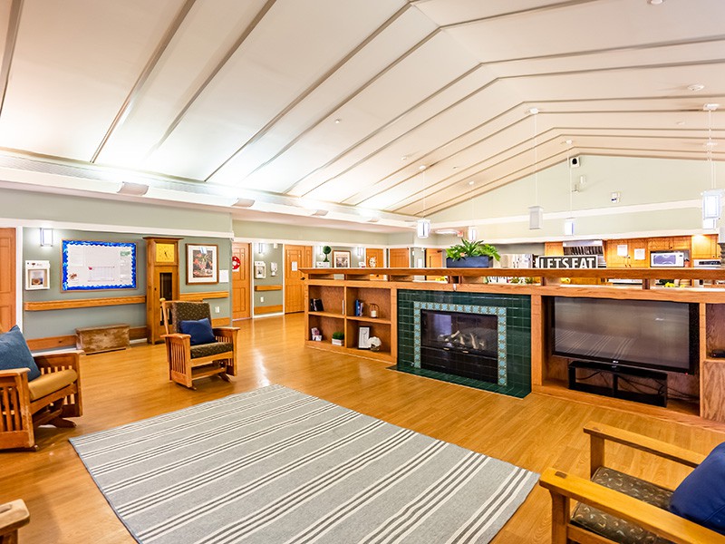 A spacious living room with a modern architectural design featuring wooden furniture, a fireplace, and built-in bookshelves.