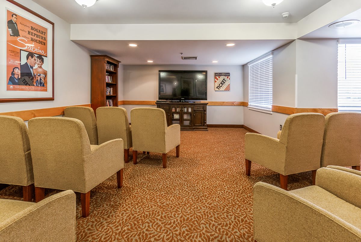 A cozy conference room with arranged seating facing a large television.