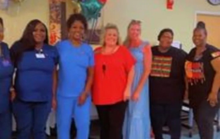 A group of people smiling and standing together indoors.