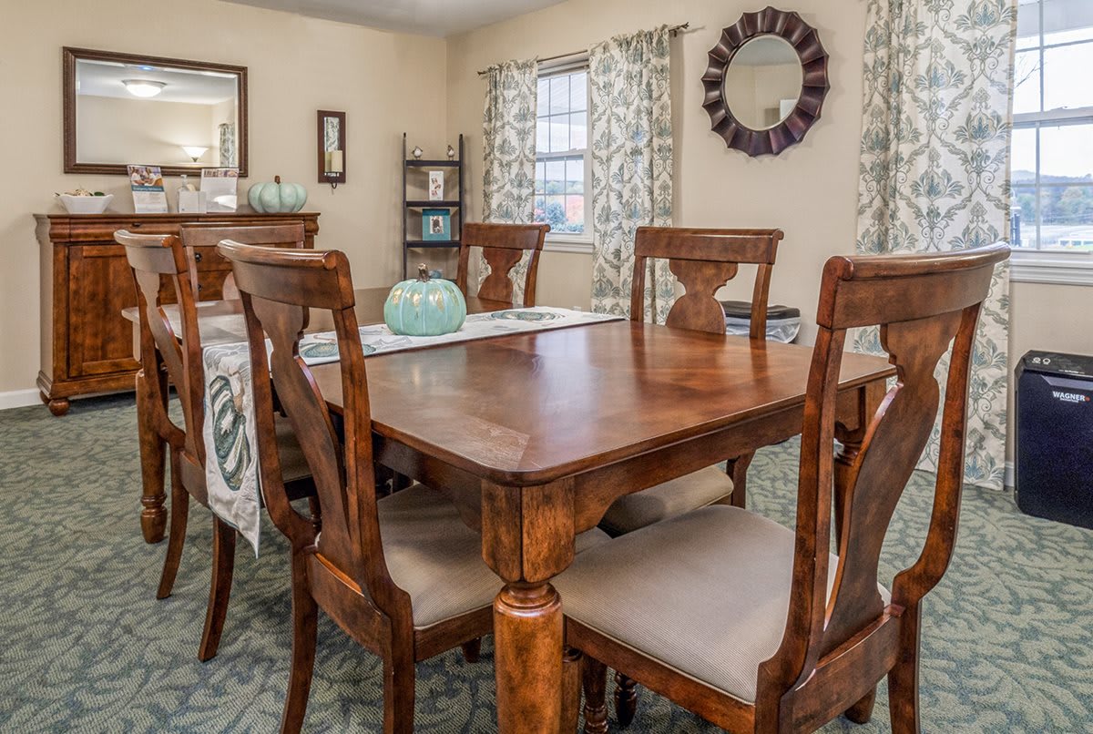 A cozy dining room featuring a wooden table with matching chairs, adorned with elegant home decor and curtains.