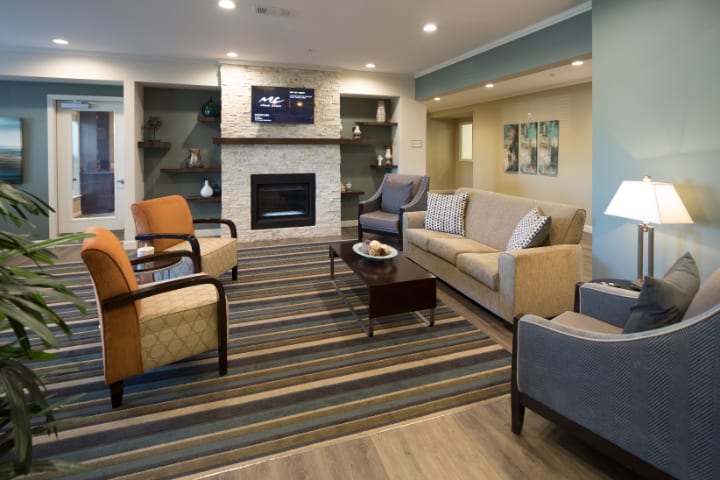 A modern living room with a cozy seating arrangement around a fireplace and television.