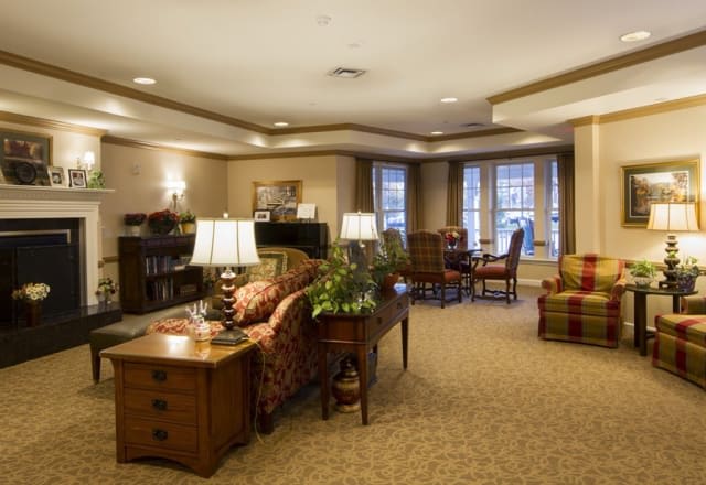 A cozy living room interior with sofas, tables, and lamps in a warmly lit space.